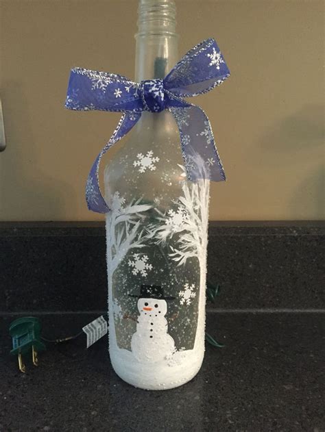 A Glass Bottle With A Snowman Painted On It And A Blue Ribbon Around