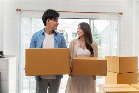 Premium Photo Couple Holding Cardboard Boxes For Moving To A New House