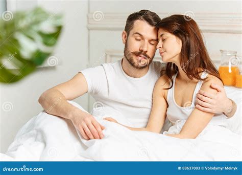 Young Adult Heterosexual Couple Lying On Bed In Bedroom Stock Image