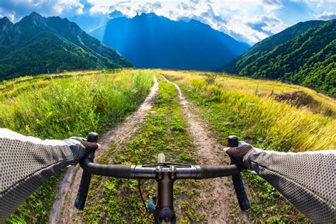 Hands On The Handlebars Of A Bicycle Of A Cyclist Riding Along A Trail