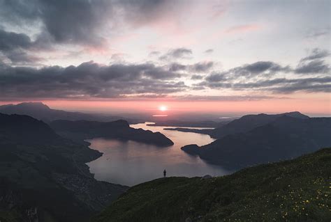 Silhouette Of Person Standing On Lake Surrounded By Mountains Under