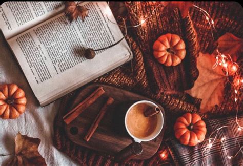 An Open Book Cup Of Coffee And Some Pumpkins On A Table With Lights