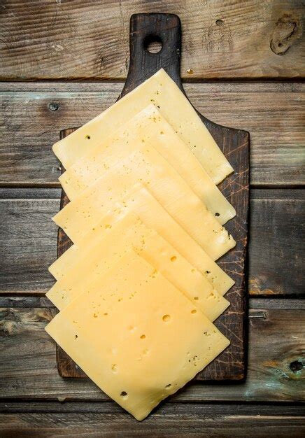 Delgadas Lonchas De Queso En La Tabla De Cortar Sobre Una Superficie