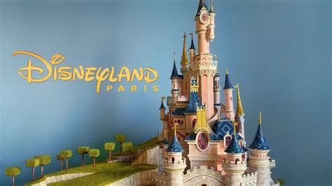 There Is A Model Of A Castle In The Background With Disney Land Written