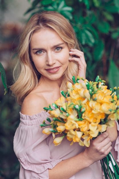 Portrait De Jeune Femme Blonde Souriante Tenant Des Fleurs Jaunes Photo Gratuite