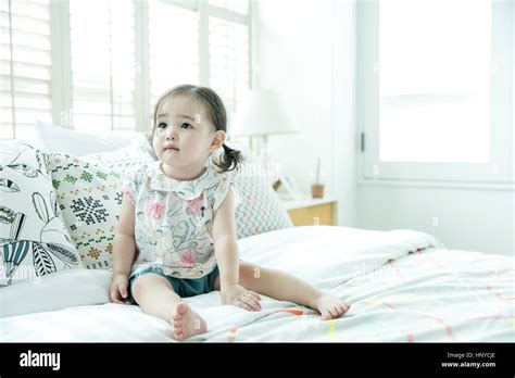 Baby Girl Sitting On Bed Stock Photo Alamy