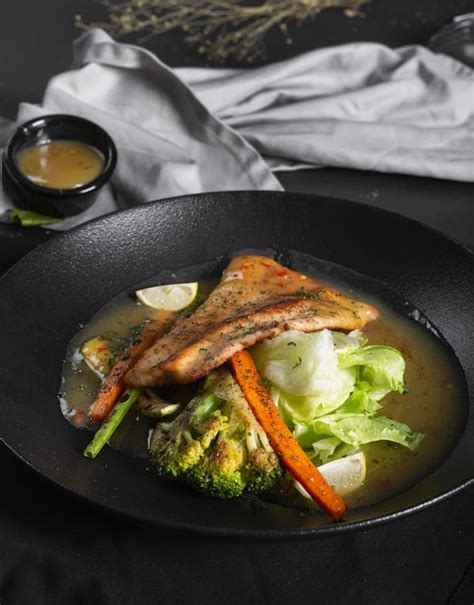 Un Plato De Comida Con Un Trozo De Pescado Y Verduras Foto Premium