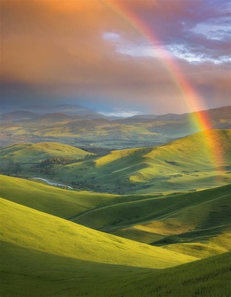 A Rainbow Arching Over A Lush Green Valley Sevenart