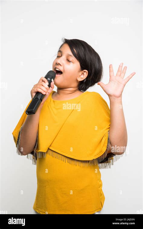 Cute Little Indian Girl Singing In Microphone Standing Isolated Over