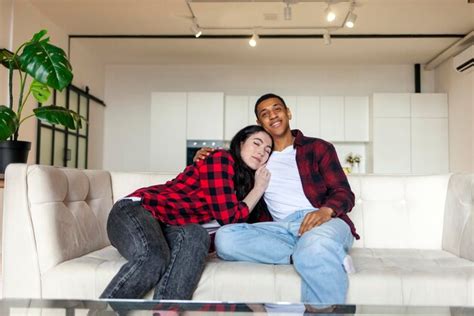 Premium Photo Young Happy Multiracial Couple Sitting On Sofa At Home