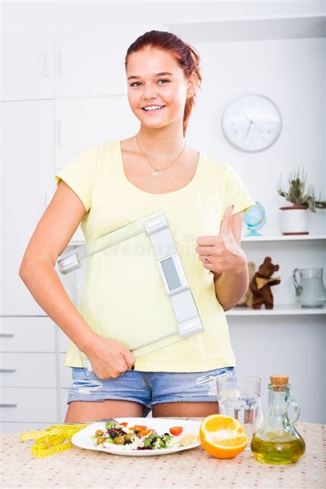 Muchacha Que Se Coloca Con Las Escalas En Cocina Imagen De Archivo