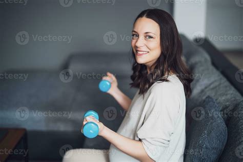 Pregnant woman is exercising with weights at home. 23255211 Stock Photo ...