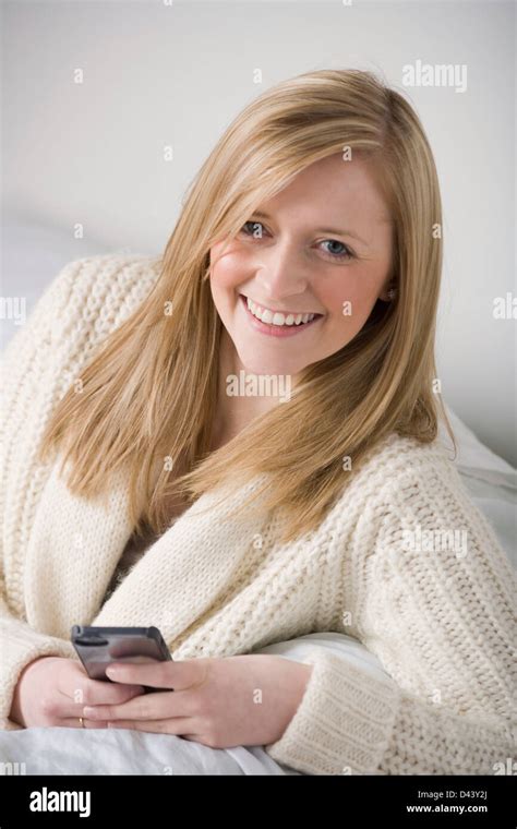 Pretty Blonde Woman Holding A Mobile Phone Sitting On A Sofa Stock Photo Alamy