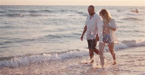 Couple of Young Lovers Holding Hands Walking Along the Beach By the Sea ...