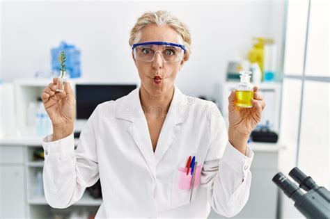 Middle Age Blonde Woman Working At Laboratory Making Fish Face With