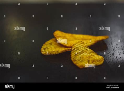 Crisps Hot And Spicy Potato Chips Ready To Eat On The Table With Green Plant Background Stock