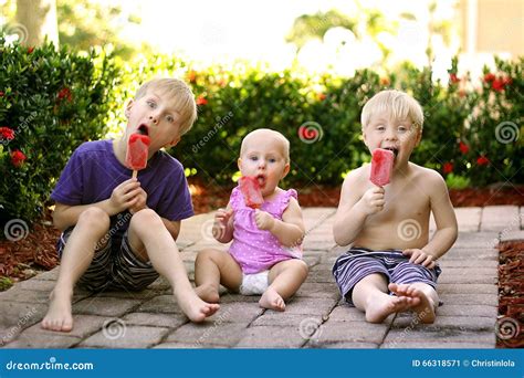 Three Children Eating Fruit Popsicles Outside On Summer Day Stock Image