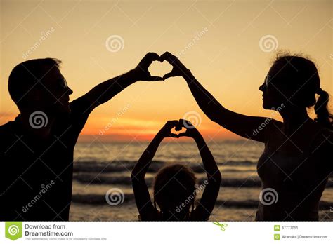 Silueta De La Familia Feliz Que Juega En La Playa En El Sunse Imagen De