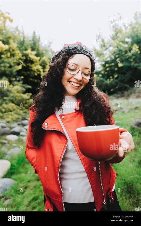 Smiling Curly Brunette Woman Wearing A Red Leather Jacket And Holding