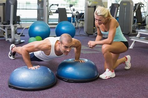 Premium Photo Trainer Assisting Man With Push Ups At Gym