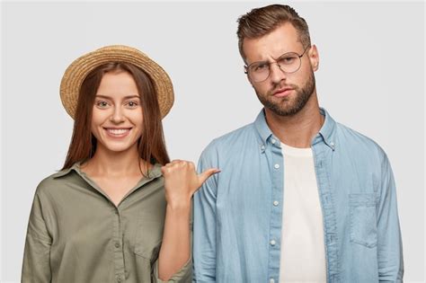 Женщина в соломенной шляпе с широкой сияющей улыбкой указывает на ...