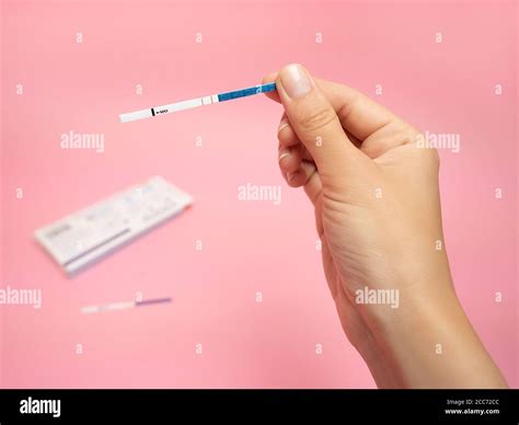 Female Hand Holding Positive Pregnancy Test Isolated On Pink Background