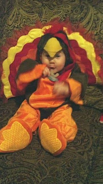 A Baby Dressed As A Turkey Sitting On Top Of A Couch