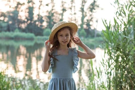 Una Chica Con Vestido Azul Y Sombrero De Paja Se Encuentra En La Orilla