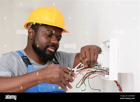 African American Electrician Performing Wiring In Room Stock Photo Alamy