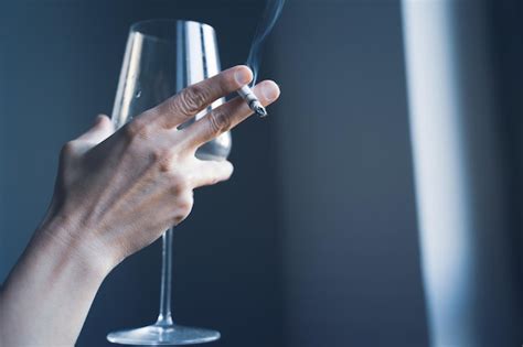 Closeup de mãos de mulher segurando um cigarro e um copo de vinho