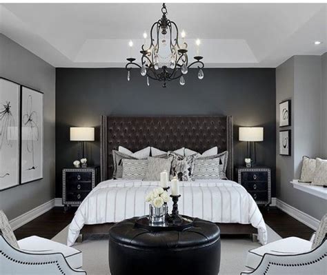 A Bedroom With Gray Walls White Bedding And Chandelier Hanging From