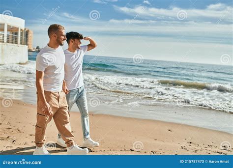 Jovem Casal Gay Sorrindo Feliz Caminhando Na Praia Imagem De Stock