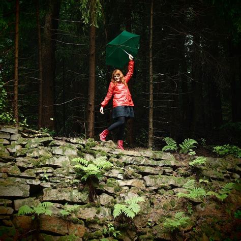 Premium Photo Happy Woman In Raincoat With Umbrella Standing On Stone Wall At Forest