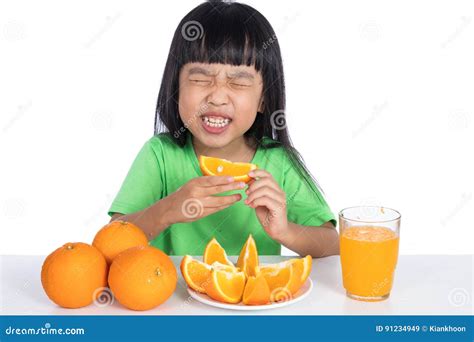 Asian Chinese Little Girl Eating Sour Orange And Making Grimace Stock