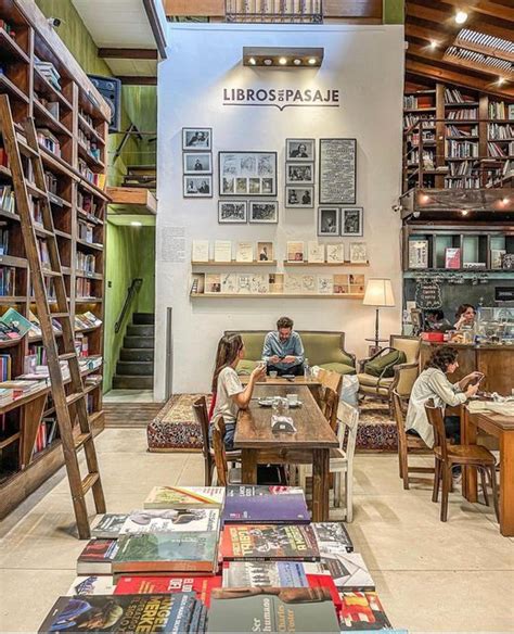 People Sitting At Tables In A Library With Bookshelves And Ladders On