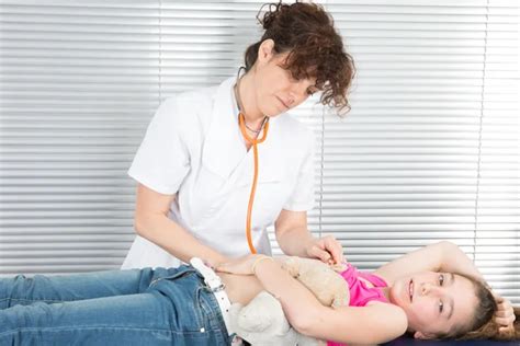 Smiling Doctor Examining Or Massaging Girl Stomach Isolated On White