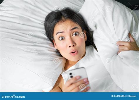 Portrait Of Asian Girl Wakes Up In Morning Looks At Mobile Phone With