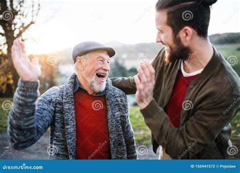 Laughing Senior Father And His Son On Walk In Nature Giving High Five