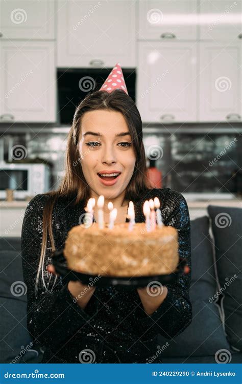 Young Woman Blowing Out Candles On A Birthday Cake A Girl Alone In A