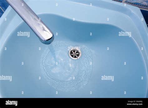 Water Flows From The Tap In A Blue Washbasin The Liquid Pours Out