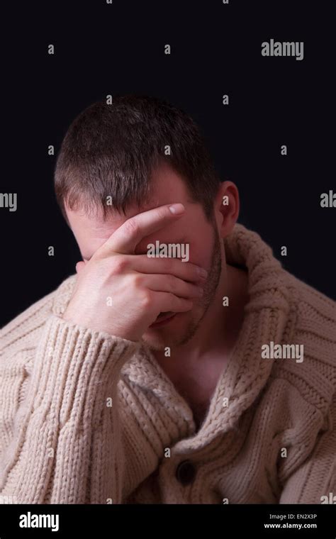 Upset man covers his face with a hand, black background Stock Photo - Alamy