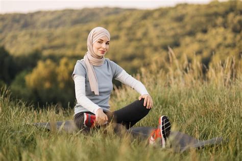 Feliz joven deportista en hiyab y ropa activa estirando los músculos de