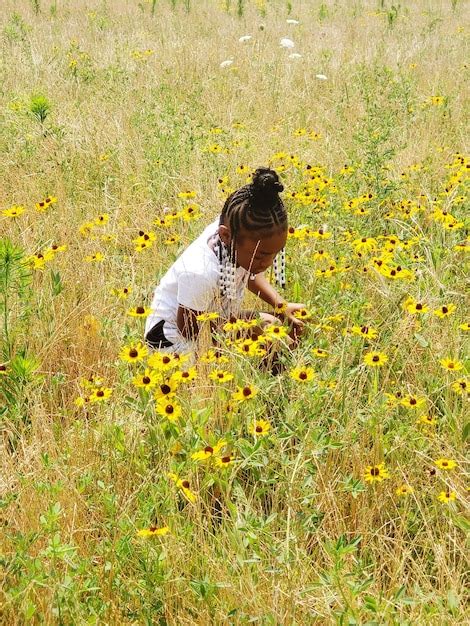 Premium Photo High Angle View Of Girl Crouching Amidst Flowers On Land