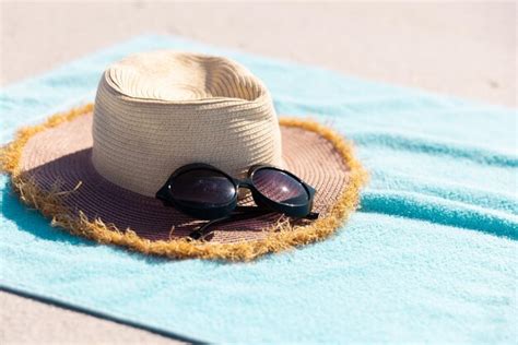 Premium Photo Close Up Of Sunglasses And Hat On Blue Towel At Beach During Sunny Day