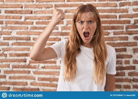 Young Caucasian Woman Standing Over Bricks Wall Angry And Mad Raising Fist Frustrated And