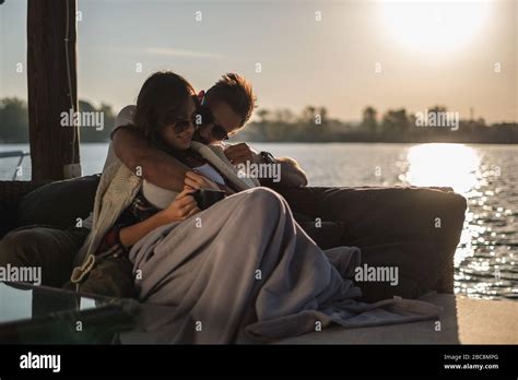 Man Hugging His Girlfriend While She Is Lying By The River Covered With