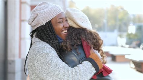 Two Multiracial Female Happy Friends Hugging Each Other On City Street