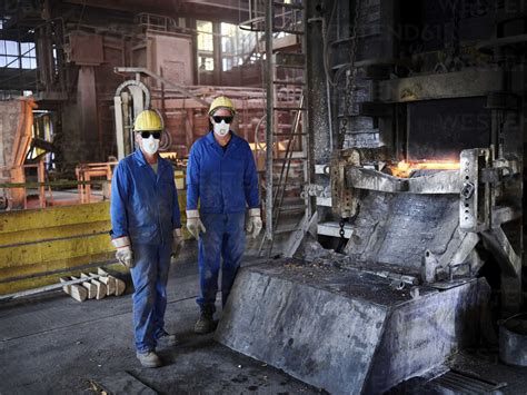 Industry, Smeltery: Workers in front of blast furnace with helmet and dust mask stock photo