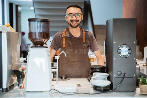 Male Barista Smiling At Camera Standing Behind Barista Counter Stock