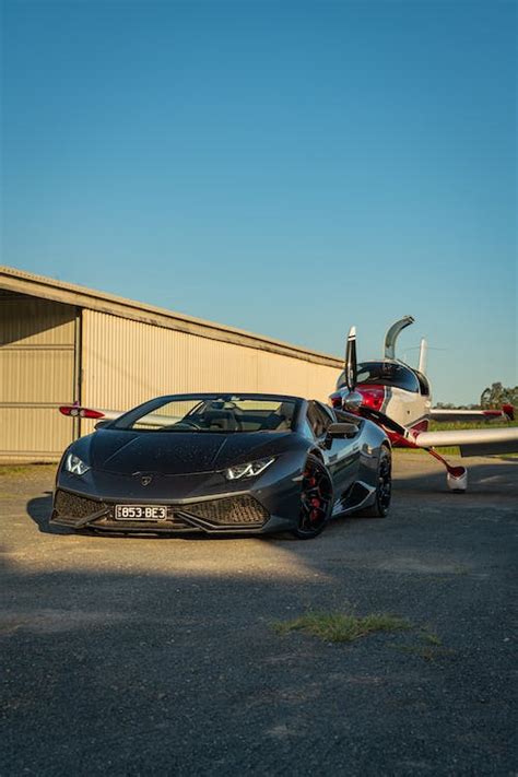 Lamborghini in front of the sports plane in the airfield during sunset ...